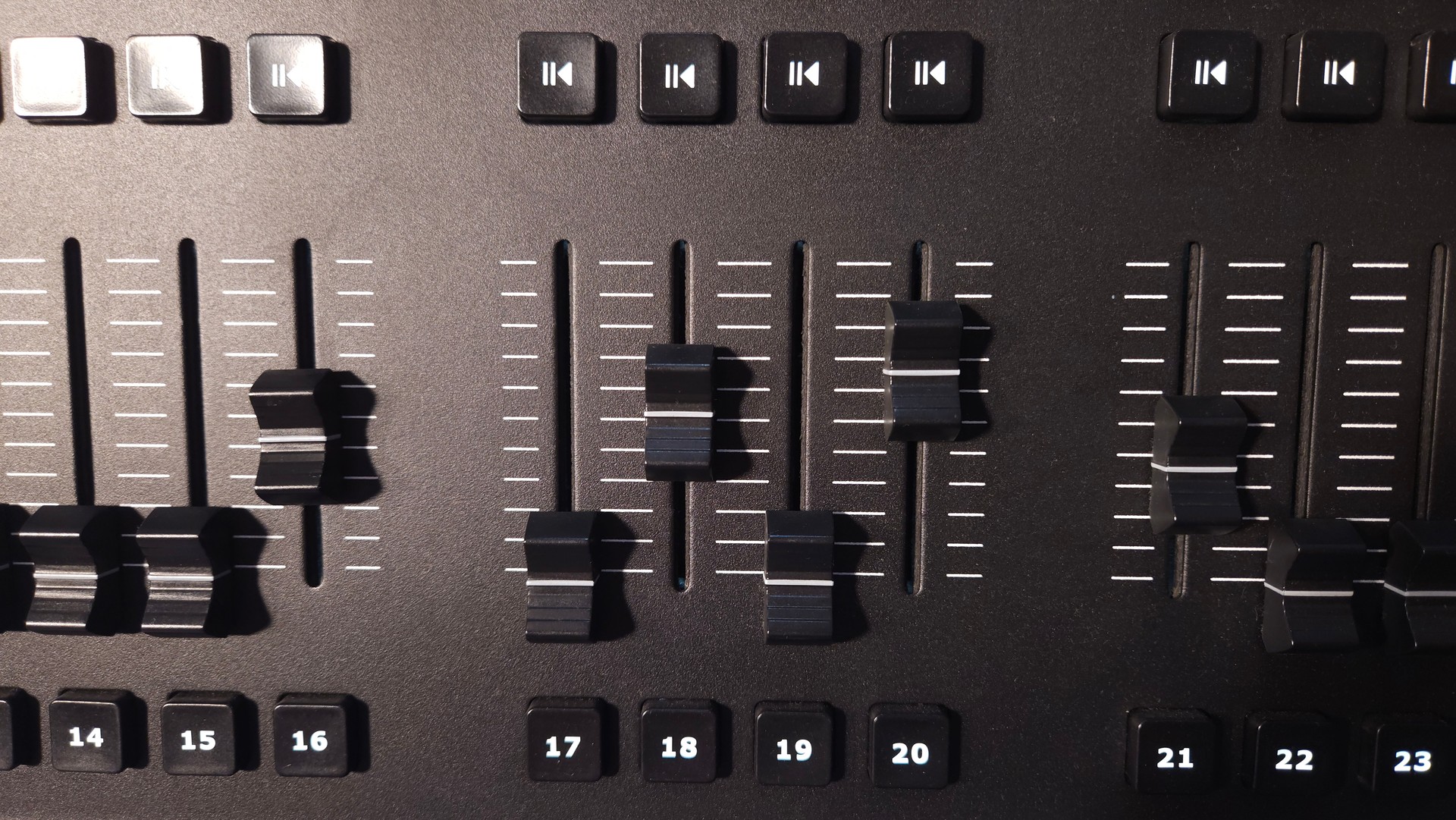 Close-up view of fader sliders and control buttons on a professional lighting control panel. Close-up view of fader sliders and control buttons on a professional lighting control panel.